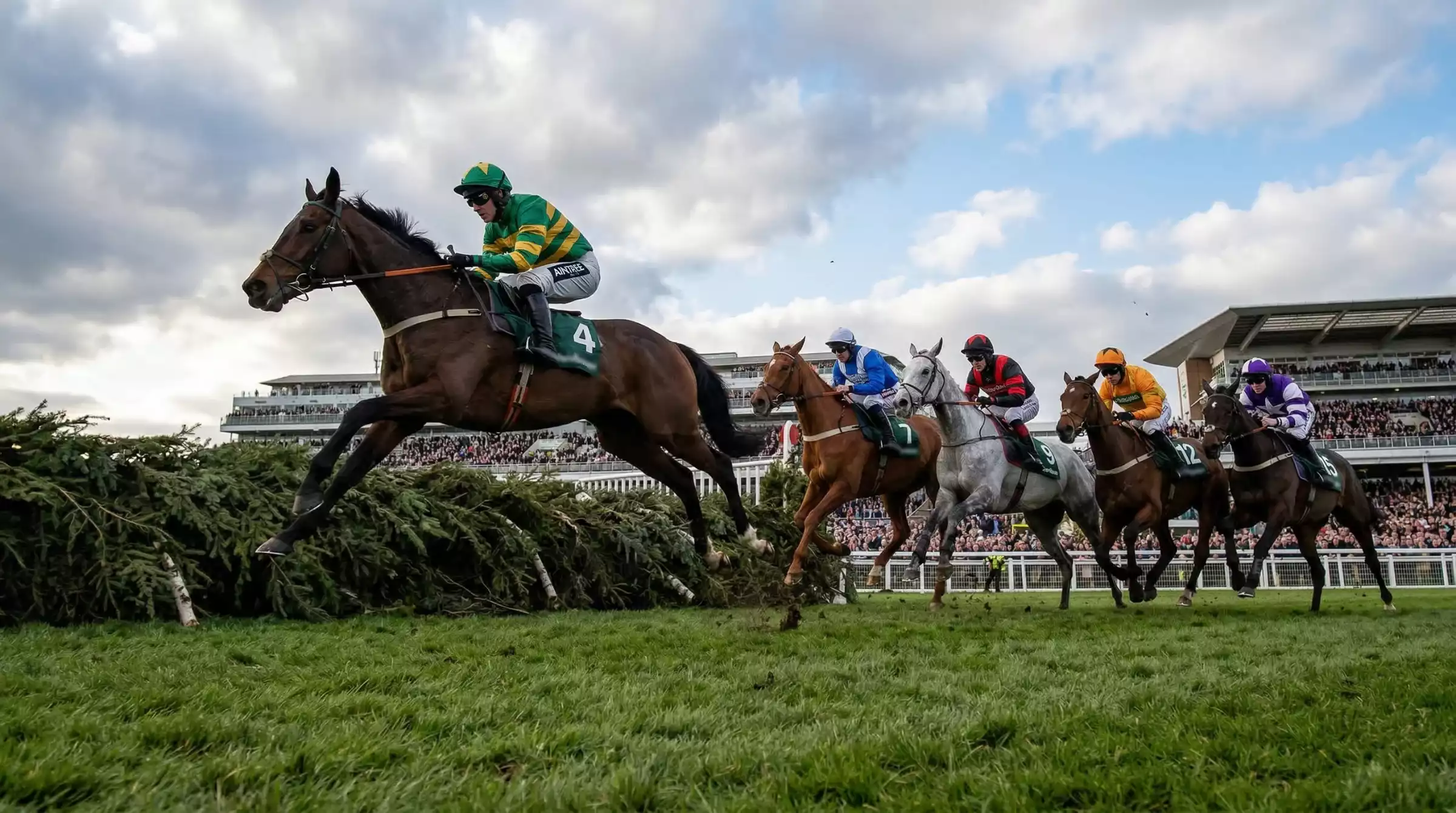 Grand National horse racing at Aintree racecourse with jockeys jumping a fence
